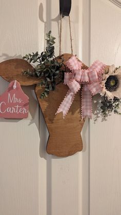 a wooden moose head hanging on a door with pink and white flowers in the center