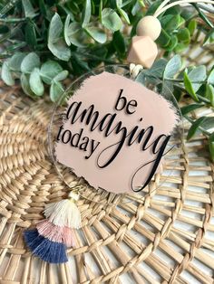 a glass ornament with the words be amazing today and tassels on it