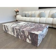 a marble coffee table sitting on top of a hard wood floor next to a white couch