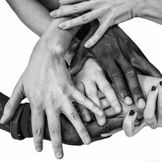 a group of people's hands stacked on top of each other in black and white