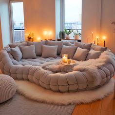 a living room filled with lots of furniture next to tall windows and candles on the floor