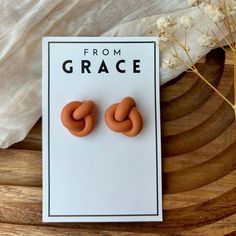 a pair of orange earrings sitting on top of a wooden table next to a plant