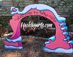 a welcome sign to the front yard of a house with pink and blue waves on it