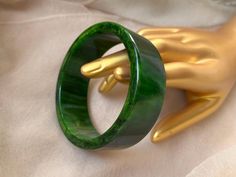 This bangle bracelet is made of Bakelite/Catalin (phenolic resin) and features gorgeous shades of dark green and yellow swirled together making a excellent marbled effect. It has a wide, flat shape and is fairly lightweight for a Bakelite bangle. It been simichrome tested and positively identified as genuine Bakelite/Catalin.  It measures 3" across and is 15/16" wide. It has small signs of wear and age as is normal for vintage plastics, but it is generally in very good condition. Boho Art Deco, Mid Century Boho, Bakelite Bangles, Flat Shapes, Vintage Bakelite, Wide Bracelet, Boho Art, Dark Green, Swirl