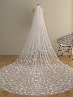 a wedding veil with white birds on it is shown in front of a chair and table