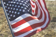 an american flag is being held in the air by someone's hand, with other people behind it