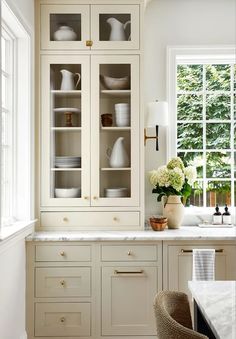 a kitchen filled with lots of white cupboards and counter top space next to a window