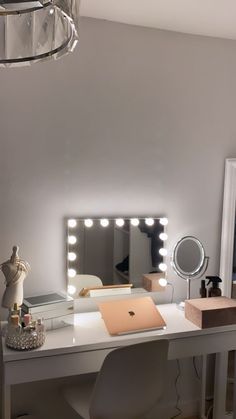 a white desk topped with a laptop computer under a mirror next to a light fixture