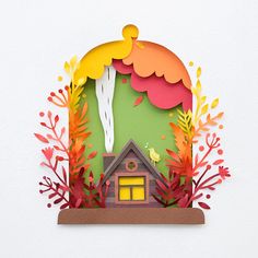 a paper cut house surrounded by autumn foliage