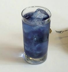 a glass filled with blue liquid sitting on top of a table