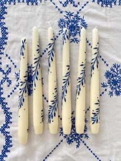 four white candles sitting on top of a blue and white table cloth