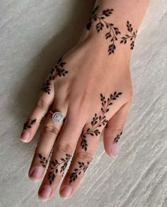 a woman's hand with black henna tattoos on her left wrist and fingers