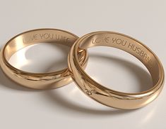 two gold wedding rings with i love you husband written on them