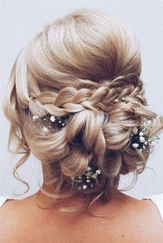 the back of a woman's head with braids and flowers in her hair