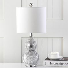 a table with a lamp on top of it next to a book and coffee cup