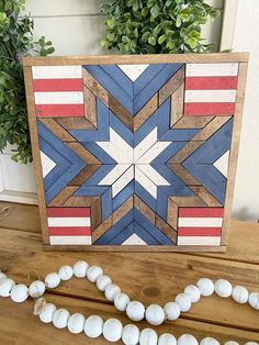 a wooden frame with an american flag design on it next to some seashells