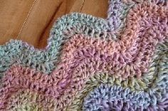 a multicolored crocheted blanket laying on top of a wooden floor