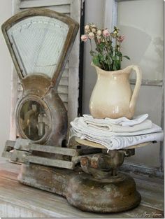 an old scale with flowers in a vase on top of it next to other items