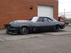 a gray car parked in front of a brick building