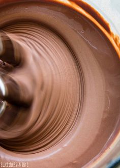 a close up view of a bowl with some food in it and someone is making something out of clay