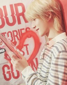 a woman is reading a book in front of a red wall