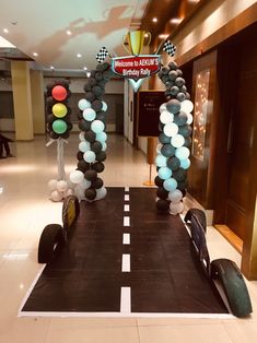 a car made out of balloons in the middle of a lobby with a traffic light