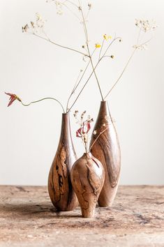 three wooden vases with flowers in them on a table