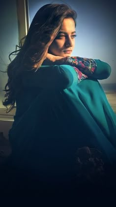 a woman with long hair sitting in front of a window