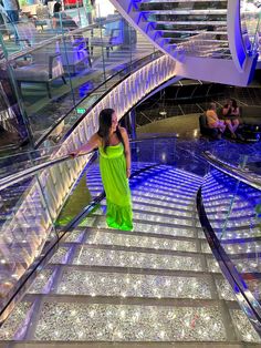 a woman in a green dress is walking down the stairs on an escalator