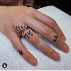 a woman's hand with two small tattoos on her left and the other half of her finger