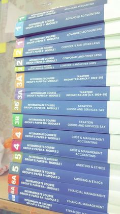 a stack of blue business books sitting on top of a wooden table in front of a window