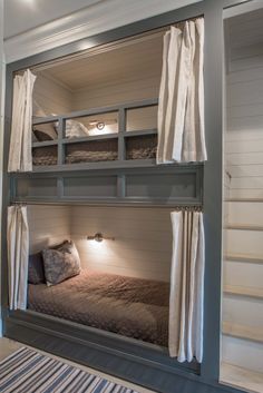 bunk beds are built into the side of a wall with curtains on them and lights on