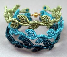 a close up of a bracelet on a white surface with blue and green thread work