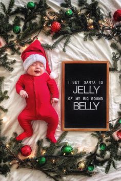 a baby wearing a santa hat is laying next to a sign that says jelly of my big round belly