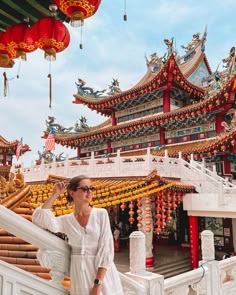 a woman standing on the stairs in front of a building with red lanterns hanging from it