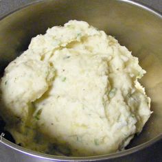 a metal bowl filled with mashed potatoes on top of a counter