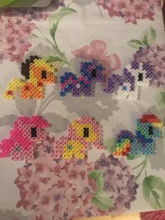 flowers made out of perler beads on a white background with pink, yellow and blue flowers