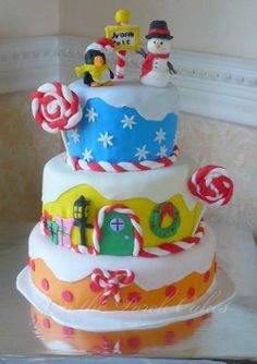 a three tiered cake decorated with candy canes and snowmen on top is sitting on a table