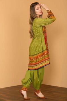 a woman in green is standing on a wooden floor with her hands behind her head