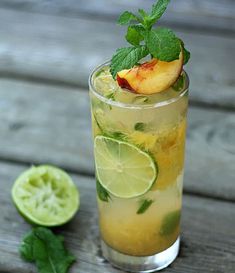 a tall glass filled with lemonade and mint garnish next to a sliced lime