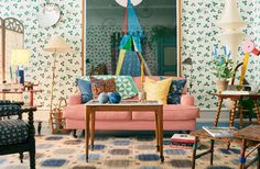 a living room filled with lots of furniture and colorful wallpaper on the walls,