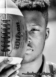 a black and white photo of a young man holding a football in his right hand