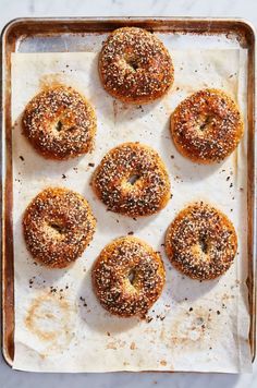 six bagels sitting on top of a baking sheet covered in sprinkles