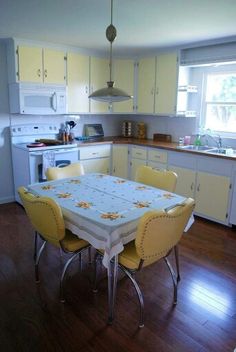 a kitchen with yellow chairs and a white table in the middle of it, next to an oven