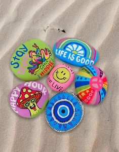 several different colored buttons on the sand with words and pictures written on them to describe what life is good