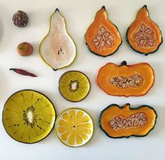 various fruits and vegetables are arranged on a white surface, including oranges, pears, and an avocado