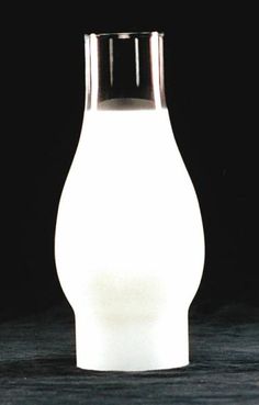 a white vase sitting on top of a wooden table next to a black wall and floor