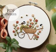 a close up of a embroidery on a hoop with flowers and birds in the wheel