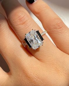 a woman's hand with a ring on it and an engagement ring in the middle