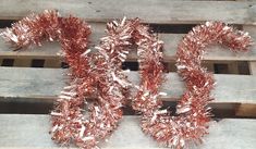 some tinsel wrapped wreaths on top of wooden pallets with red tinsel